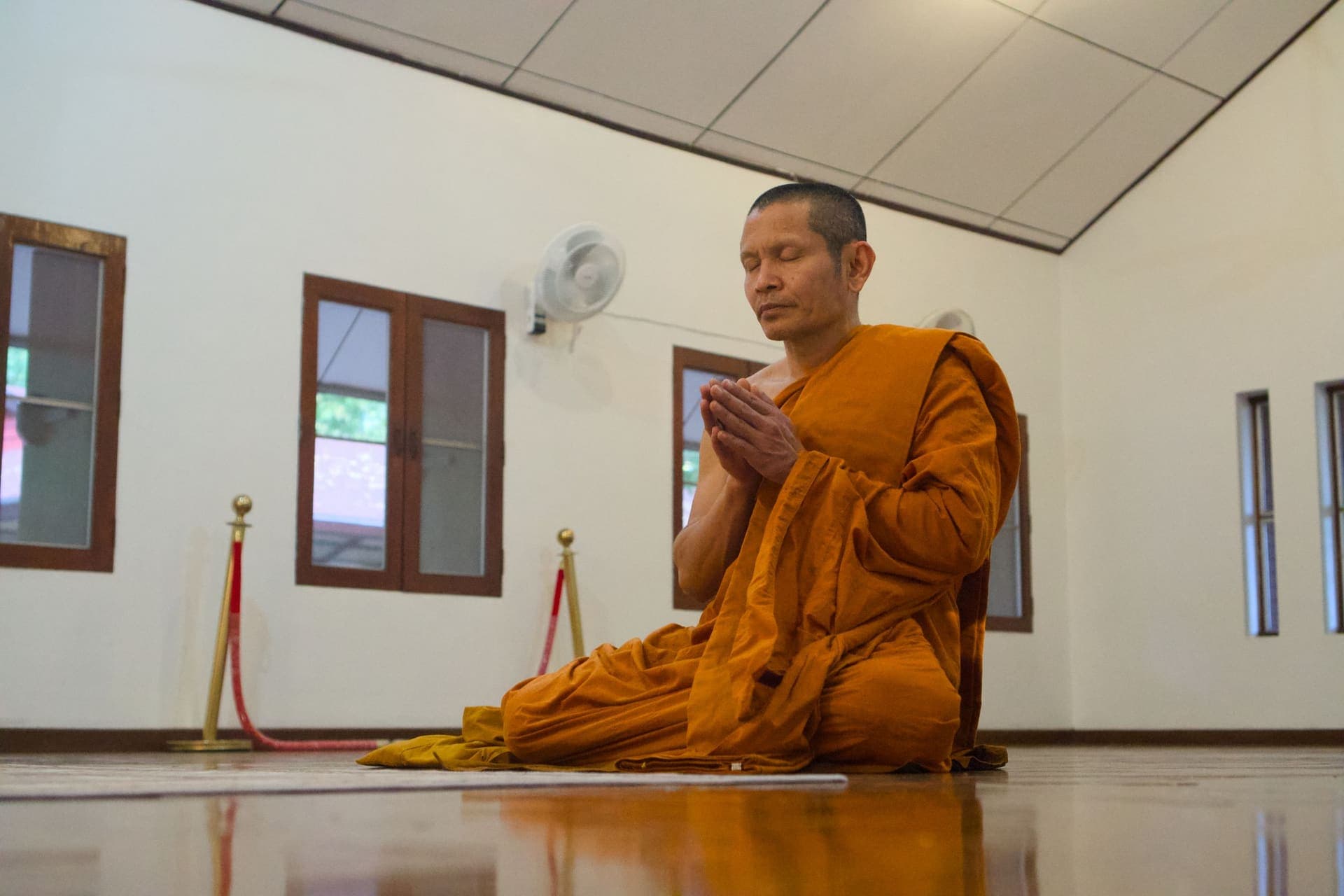 A Buddhist monk in orange robes meditating in a Chiang Mai temple.
